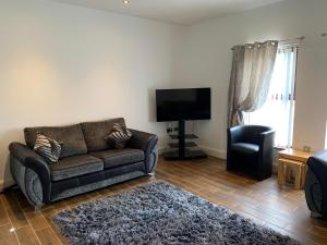 ein Wohnzimmer mit einem Sofa und einem TV in der Unterkunft 3 bedroom detached bungalow in Dromore