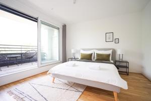 Dormitorio blanco con cama y ventana grande en Green Garden Apartment w/.Balcony near Thermal Spa, en Viena