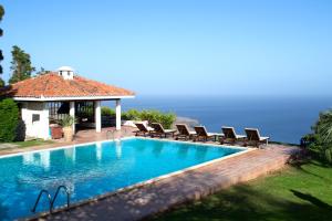 a swimming pool with chairs and the ocean in the background at Villas La Gomera in Alajeró