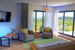 a room with a bed and two chairs and a large window at Villa Vintana Nosy Be in Nosy Be