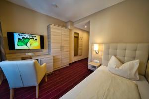 a bedroom with a bed and a flat screen tv at Hotel Tenner in Neustadt an der Weinstraße