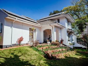una casa bianca con un giardino di fronte di Twickenham Guest House a Johannesburg