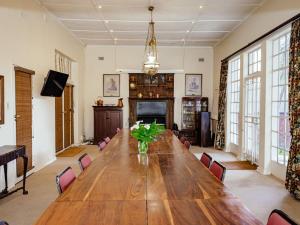 una grande sala da pranzo con tavolo e sedie in legno di Twickenham Guest House a Johannesburg
