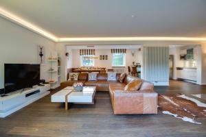 a living room with a couch and a tv at Ferienhaus Seehof mit Sauna & offenem Kamin in Schliersee