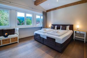 ein Schlafzimmer mit einem großen Bett und zwei Fenstern in der Unterkunft Ferienhaus Seehof mit Sauna & offenem Kamin in Schliersee