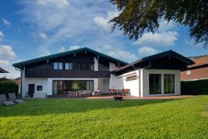 ein Haus mit grünem Rasen davor in der Unterkunft Ferienhaus Seehof mit Sauna & offenem Kamin in Schliersee