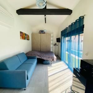 ein Wohnzimmer mit einem blauen Sofa und einem Bett in der Unterkunft Studio indépendant sur propriété avec piscine partagée in Biscarrosse