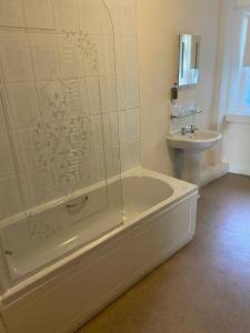 a white bathroom with a tub and a sink at George Hotel in Keswick