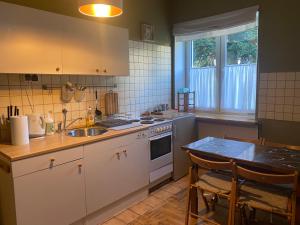kuchnia z białymi szafkami, stołem i zlewem w obiekcie Apartament u Maliny w mieście Krynica Zdrój