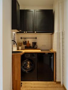 a kitchen with black cabinets and a washer at Downtown friendly studio in Bucharest +11 photos