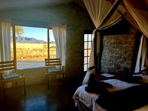 a bedroom with a bed and a window with a view at Little Sossus Lodge in Sesriem