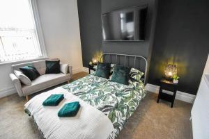 a bedroom with a bed and a couch and a television at Hesketh Villa - 4 Bedroom Seaside Holiday Home in Blackpool