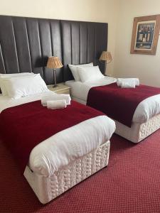 two beds in a hotel room with red and white at George Hotel in Keswick