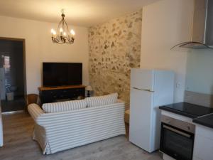 uma sala de estar com um sofá, uma televisão e um frigorífico em Joli appartement quartier Brassens 55 m2 à 2 mn du centre ville em Sète
