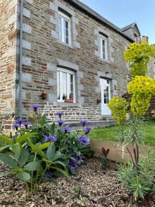 un jardín frente a una casa de ladrillo con flores en Maison de La Beslière meublé de tourisme 2 étoiles, en Folligny