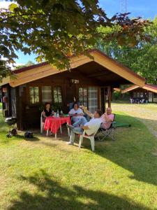 eine Gruppe von Menschen, die vor einem Haus an einem Tisch sitzen in der Unterkunft Naturpark Kanone in Markersdorf