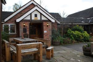 a wooden table and benches in front of a building at The Plough Inn & Restaurant in Congleton