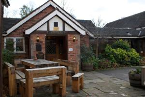 una mesa de madera y bancos frente a un edificio en The Plough Inn & Restaurant en Congleton