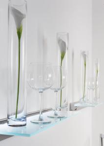 vier glazen vazen op een plank met bloemen erin bij Central Hotel in Villingen-Schwenningen