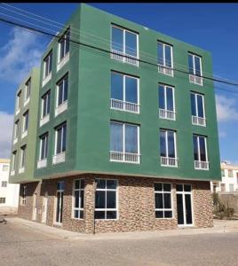 a green building on the side of a street at Apartamento T2 em Sal Rei - Boavista in Sal Rei