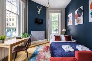een slaapkamer met blauwe muren en een bureau en een bed bij Sunny Corner Apartment in Center of London (1) in Londen