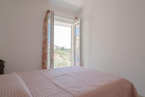 een witte slaapkamer met een bed en een raam bij Casa do Grifo - Incantevole appartamento con vista in Rovereto