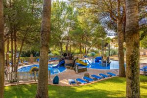 uma piscina num resort com cadeiras e um parque infantil em Valentin Park Club em Paguera