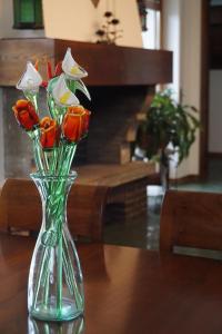 un vase en verre rempli de fleurs oranges et blanches sur une table dans l'établissement Al Picchio Verde A.P.S., à Cunardo