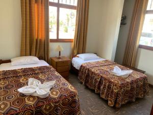 two beds in a hotel room with towels on them at Hostal El Amigo in Paracas