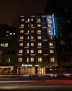 台北的住宿－柯達大飯店 台北林森，一座高大的建筑,晚上有明亮的窗户