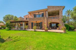 a large stone house with a green yard at Finca Santigor in Cala Ferrera
