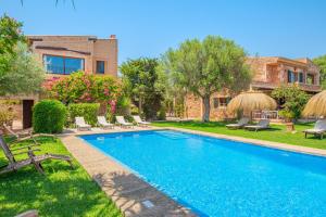 una piscina en un patio con sillas y una casa en Finca Santigor, en Cala Ferrera