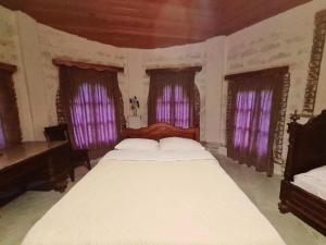 1 dormitorio con 1 cama grande y cortinas moradas en Art House Koshki, en Gurjaani