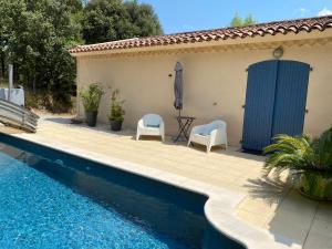 a patio with two chairs and a swimming pool at Les Garrigues Bleues in Tornac