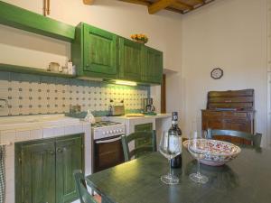 a kitchen with green cabinets and a table with wine glasses at Apartment Cellole - Cellole 2 - CTC151 by Interhome in Castellina in Chianti +25 photos