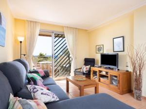 Una sala de estar con un sofá azul y un televisor en Apartment La Tejita by Interhome, en La Tejita