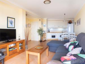 Una sala de estar con un sofá azul y un televisor en Apartment La Tejita by Interhome, en La Tejita