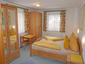 ein Schlafzimmer mit einem Bett mit gelben Kissen und einem Tisch in der Unterkunft Apartment Christina by Interhome in Pettneu am Arlberg