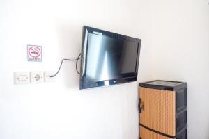 une télévision suspendue sur un mur à côté d'un haut-parleur dans l'établissement ReDdoorz At Mahameru Residence Yogyakarta, à Yogyakarta