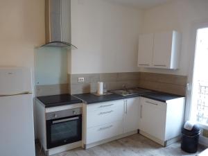 uma cozinha com armários brancos, um lavatório e um frigorífico em Joli appartement quartier Brassens 55 m2 à 2 mn du centre ville em Sète