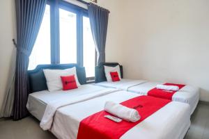 - 2 lits dans une chambre rouge et blanche dans l'établissement ReDdoorz At Mahameru Residence Yogyakarta, à Yogyakarta
