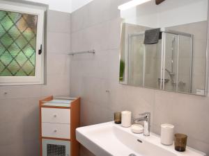 ein weißes Badezimmer mit einem Waschbecken und einem Spiegel in der Unterkunft Apartment Miralago - Utoring-25 by Interhome in Piazzogna