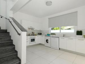 eine weiße Küche mit weißen Schränken und einer Treppe in der Unterkunft Villa paloma by Interhome in Paralimni