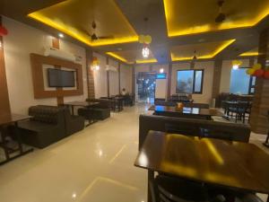 a restaurant with tables and chairs and yellow ceilings at Hotel Broadway By WB Inn in Amritsar