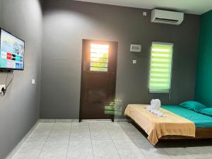 a bedroom with a bed and a tv in a room at Tok Abu Heritage Roomstay in Pantai Cenang