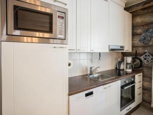 a kitchen with white cabinets and a microwave at Holiday Home Maahisenrinne 1 as 4 by Interhome in Äkäslompolo