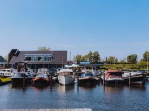 een groep boten aangemeerd in het water bij een gebouw bij Holiday Home De Meerparel-7 in Uitgeest