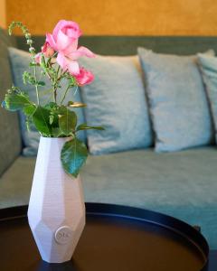 eine rosa Rose in einer weißen Vase auf einem Tisch in der Unterkunft KOKON Apartments in Leutasch