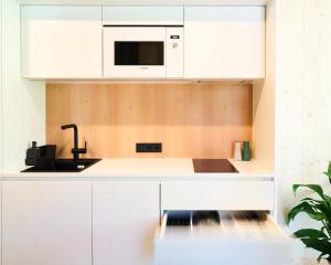 eine weiße Küche mit einer Spüle und einer Mikrowelle in der Unterkunft KOKON Apartments in Leutasch