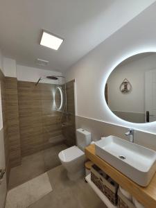 ein Badezimmer mit einem Waschbecken, einem WC und einem Spiegel in der Unterkunft AmuraHouse. Private terrace BBQ. Centric and cosy. in Cotillo